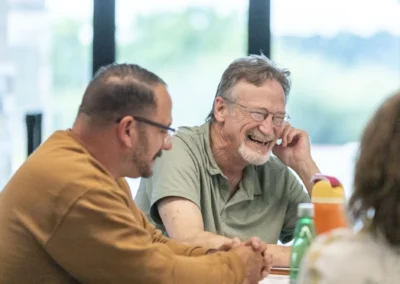Two participants share a laugh at the Lived Experience Committee meeting table.