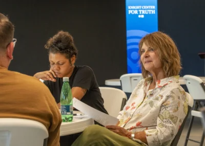 Participants listen to a speaker across the Lived Experience Committee meeting table.