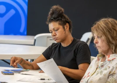 Two participants review papers at the Lived Experience Committee meeting table.