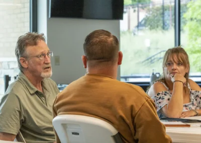Three participants exchange ideas during the Lived Experience Committee meeting.